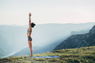 Gün batımında yoga yapan zinde bir genç kız.