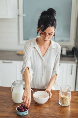 Güzel genç bayan mutfakta kahvaltı hazırlıyor.