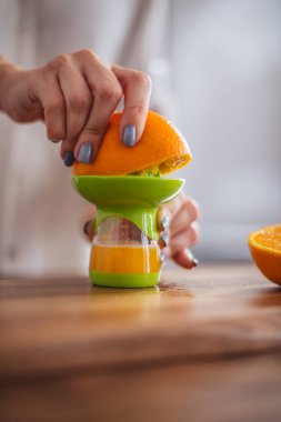 Kadın mutfakta portakal suyu yapıyor.