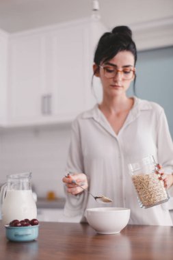 Güzel genç bayan mutfakta kahvaltı hazırlıyor.