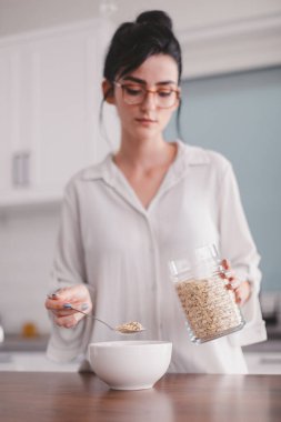 Güzel genç bayan mutfakta kahvaltı hazırlıyor.