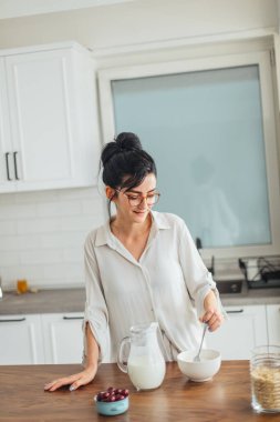 Güzel genç bayan mutfakta kahvaltı hazırlıyor.