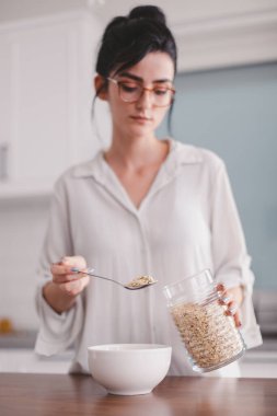 Güzel genç bayan mutfakta kahvaltı hazırlıyor.