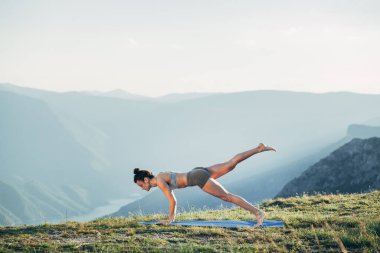 Gün batımında yoga yapan zinde bir genç kız.