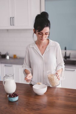 Güzel genç bayan mutfakta kahvaltı hazırlıyor.