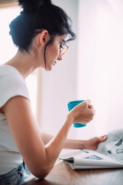 漂亮的年轻女子在厨房看报纸 — 图库照片