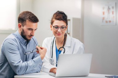 Doktor ve stajyer laptopta test sonuçlarına bakıyor.