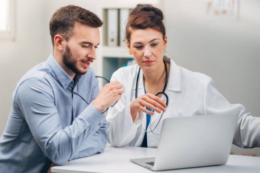 Doktor ve stajyer laptopta test sonuçlarına bakıyor.