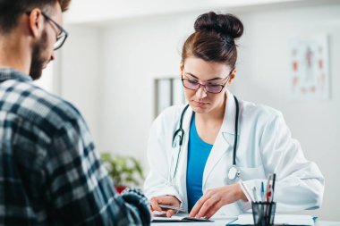 Kadın doktor, hastalığını tedavi etmeden önce genç bir hastanın kimliğini okuyor.