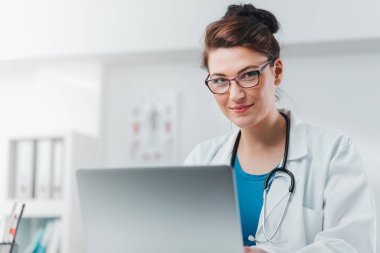 Genç Kadın Doktor 'un portresi iş üstünde dizüstü bilgisayarla çalışıyor. Hastanedeki gönüllü, hastalıkların tedavisinde pratik bilgi kazanıyor