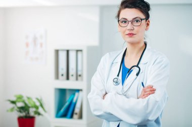 Kadın doktor steteskopla muayenehanesinde.