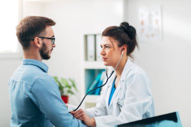 Steteskop kullanan kadın doktor hastanın göğsünü kontrol ediyor.