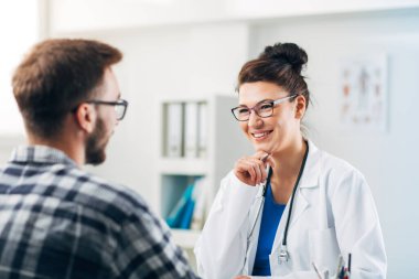 Muayenehanesindeki doktor hastasıyla konuşuyor.