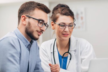 Doktor ve stajyer laptopta test sonuçlarına bakıyor. Yakın plan.
