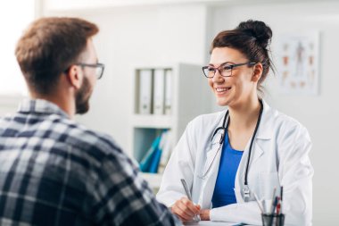 Muayenehanesindeki doktor hastasıyla konuşuyor.