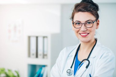 Kadın doktor steteskopla muayenehanesinde.