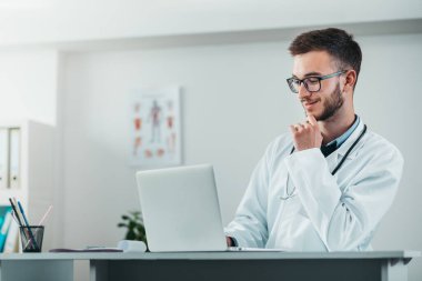 Laptop üzerinde çalışan genç doktorun portresi. Hastanedeki gönüllü, hastalıkların tedavisinde pratik bilgi kazanıyor