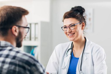 Muayenehanesindeki doktor hastasıyla konuşuyor.