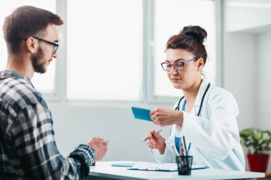 Kadın doktor, hastalığını tedavi etmeden önce genç bir hastanın kimliğini okuyor.