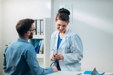 Steteskopla muayenehanesinde hasta ile konuşan kadın doktor.
