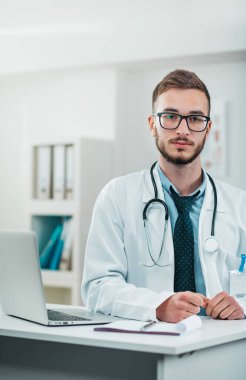 Laptop üzerinde çalışan genç doktorun portresi. Hastanedeki gönüllü, hastalıkların tedavisinde pratik bilgi kazanıyor