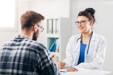 Muayenehanesindeki doktor hastasıyla konuşuyor.