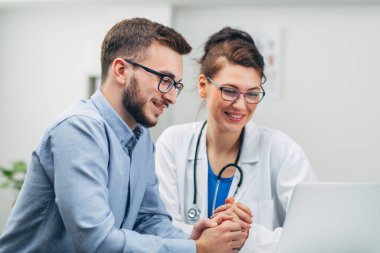 Doktor ve stajyer laptopta test sonuçlarına bakıyor. Yakın plan.