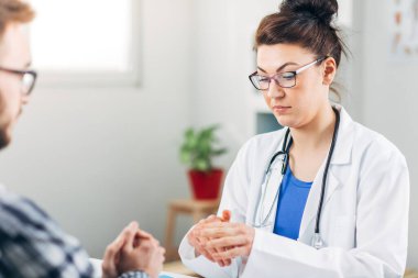 Muayenehanesindeki doktor hastasıyla konuşuyor.