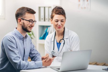 Doktor ve stajyer laptopta test sonuçlarına bakıyor.