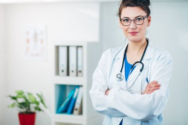 Kadın doktor steteskopla muayenehanesinde.