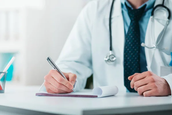 Close up of Young Doctor on the Job writing down diagnosis. Volunteer at the hospital gains practical knowledge in treating disease