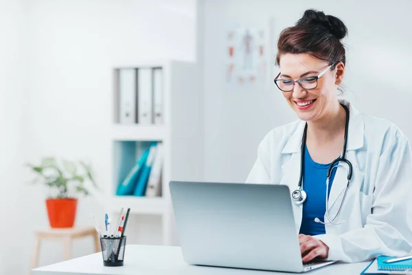 Uzman dizüstü bilgisayardan alınan sonuçlara bakıyor. Dost canlısı doktor 5 numaralı muayenehanesinde bilgisayarla çalışıyor.