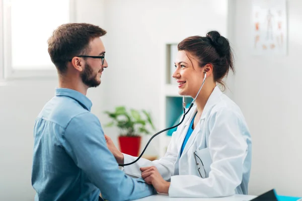 Steteskop kullanan kadın doktor hastanın göğsünü kontrol ediyor.