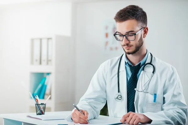 Young Doctor on the Job writing down diagnosis. Volunteer at the hospital gains practical knowledge in treating disease