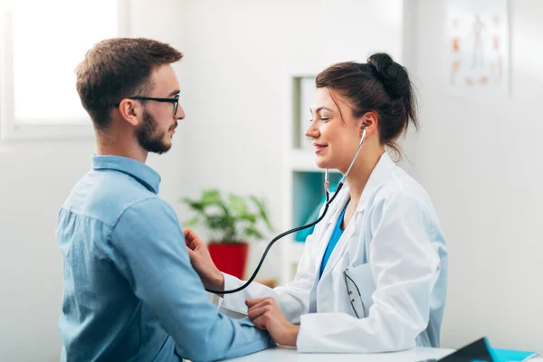Steteskop kullanan kadın doktor hastanın göğsünü kontrol ediyor.
