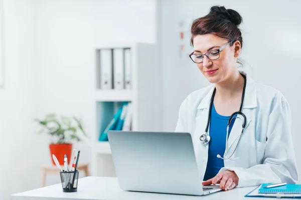Uzman dizüstü bilgisayardan alınan sonuçlara bakıyor. Dost canlısı doktor 5 numaralı muayenehanesinde bilgisayarla çalışıyor.
