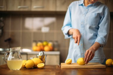Genç bir kadın mutfakta limon kesiyor.