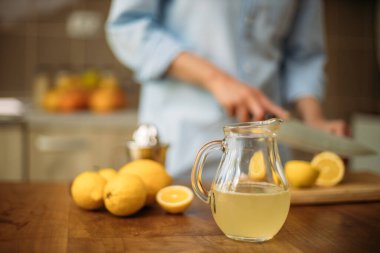Limonata ve limon kesen bir kadın.