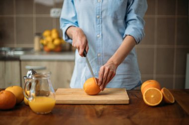Mutfakta turuncu kesen genç bir kadın.