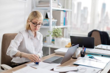 Ofisteki kadın bilgisayarda çalışıyor. Bir belgeye pul yapıştırmak