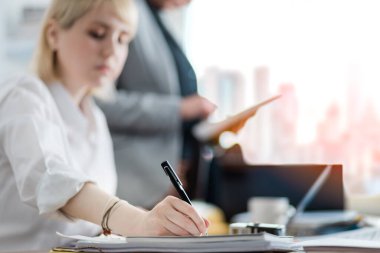 Genç iş kadını ofiste bir belge imzalıyor.