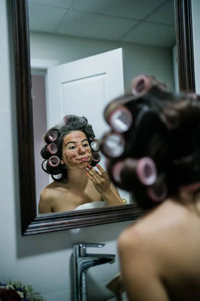 Young beautiful woman with a coffee scrub on her face doing peeling skin