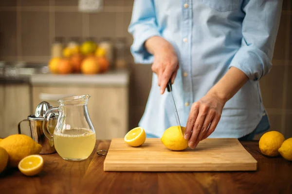 Young woman cutting lemon in the kitchen