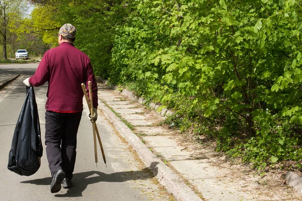 Gönüllü erkek taşıyan çöp çöp parkta arkadan görünüş