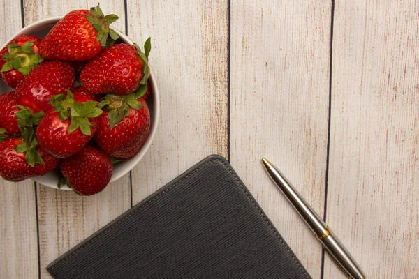 Çilek, tablet ve kalem yaz ahşap arka plan