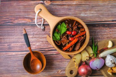 Ahşap arka planda kara biber eti ve malzemeleri var.