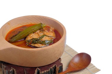 Beyaz arka planda izole edilmiş ahşap tencerede bulunan geleneksel Malezya balık yemeği Asam Pedas