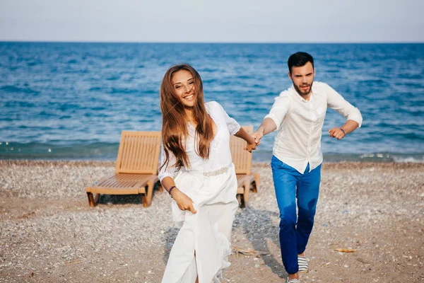 Счастливая молодая пара на пляже в любви обнимает и обнимает улыбаясь — стоковое фото