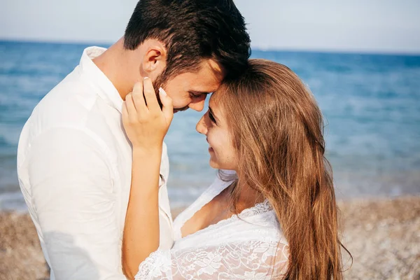 Счастливая молодая пара на пляже в любви обнимает и обнимает улыбаясь — стоковое фото
