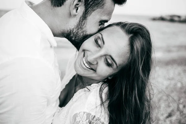 Gelukkig jong koppel op het strand in liefde omarmen en knuffelen glimlachen — Stockfoto